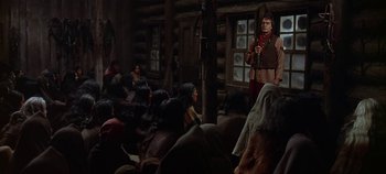 Movie still from “Cheyenne Autumn” (1964), directed by John Ford – A group of people sitting in front of a building; Wide shot, Over the shoulder angle