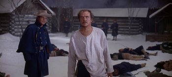 Movie still from “Cheyenne Autumn” (1964), directed by John Ford – A man standing in front of a group of dead people; Medium shot, Over the shoulder angle