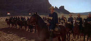 Movie still from “Cheyenne Autumn” (1964), directed by John Ford – A man in a cowboy hat sitting on top of a horse; Wide shot, Over the shoulder angle