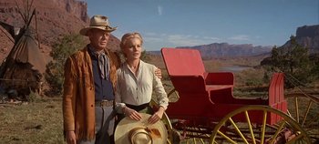 Movie still from “Cheyenne Autumn” (1964), directed by John Ford – A man and a woman standing next to each other in front of a horse drawn carriage; Medium shot, Low angle