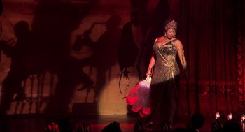 Movie still from “Chicago” (2002), directed by Rob Marshall – A woman in a gold and red dress on a stage; Wide shot, High angle