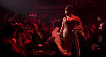 Movie still from “Chicago” (2002), directed by Rob Marshall – A woman in a dress and hat on a stage; Wide shot, Over the shoulder angle