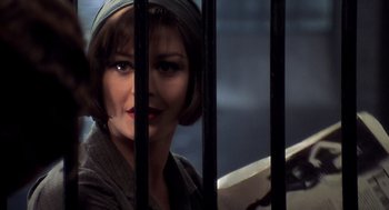 Movie still from “Chicago” (2002), directed by Rob Marshall – A woman in a hat behind bars looking at the camera; Close Up shot, Over the shoulder angle