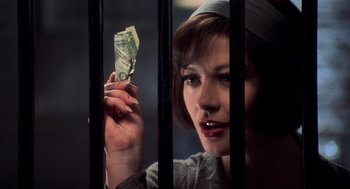 Movie still from “Chicago” (2002), directed by Rob Marshall – A woman holding a $ 1 0 0 bill behind a fence; Close Up shot, Over the shoulder angle