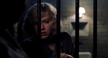 Movie still from “Chicago” (2002), directed by Rob Marshall – A woman standing behind bars in a dark room; Close Up shot, Over the shoulder angle