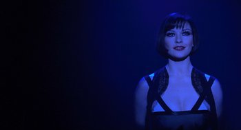 Movie still from “Chicago” (2002), directed by Rob Marshall – A woman with short hair is standing in the dark; Close Up shot, Over the shoulder angle