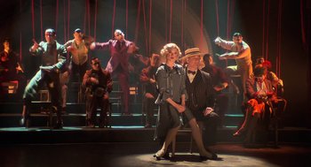 Movie still from “Chicago” (2002), directed by Rob Marshall – A group of people sitting on top of a stage; Wide shot, Low angle