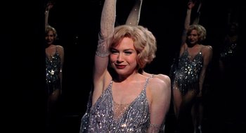 Movie still from “Chicago” (2002), directed by Rob Marshall – A woman in a sequined dress holding her arms up; Medium shot, Low angle