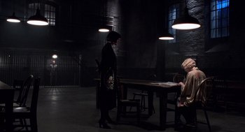 Movie still from “Chicago” (2002), directed by Rob Marshall – A woman standing next to a table in a dark room; Wide shot, High angle