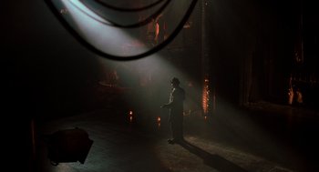 Movie still from “Chicago” (2002), directed by Rob Marshall – A man standing on a stage in the middle of a dark room; Extreme Wide shot, High angle