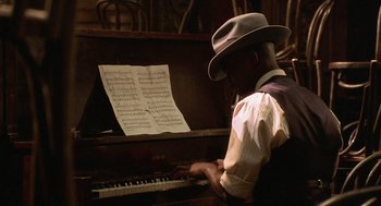 Movie still from “Chicago” (2002), directed by Rob Marshall – A man in a hat playing the piano; Medium shot, High angle