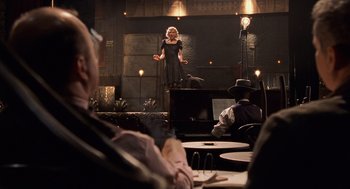 Movie still from “Chicago” (2002), directed by Rob Marshall – A woman standing in front of an audience in front of a microphone; Wide shot, Over the shoulder angle