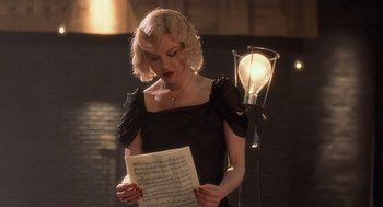 Movie still from “Chicago” (2002), directed by Rob Marshall – A woman in a black dress holding a sheet of paper; Medium shot, Over the shoulder angle