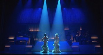 Movie still from “Chicago” (2002), directed by Rob Marshall – A couple of people that are standing in the middle of a stage; Wide shot, Low angle