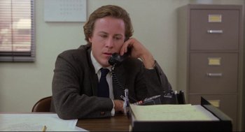 Movie still from “Chilly Scenes of Winter” (1979), directed by Joan Micklin Silver – A man sitting at a desk talking on a phone; Medium shot, Low angle