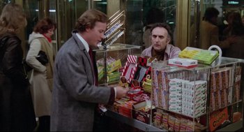 Movie still from “Chilly Scenes of Winter” (1979), directed by Joan Micklin Silver – A man in a suit and tie looking at a candy counter; Medium shot, Over the shoulder angle