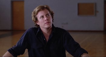 Movie still from “Chilly Scenes of Winter” (1979), directed by Joan Micklin Silver – A man with long blonde hair wearing a black shirt; Close Up shot, Low angle