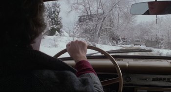 Movie still from “Chilly Scenes of Winter” (1979), directed by Joan Micklin Silver – A person driving a car in the snow; Wide shot, Over the shoulder angle