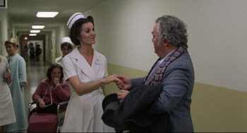 An older man and a nurse are shaking hands in a hospital
