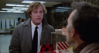 Movie still from “Chilly Scenes of Winter” (1979), directed by Joan Micklin Silver – A man in a gray coat and a black tie; Medium shot, Over the shoulder angle