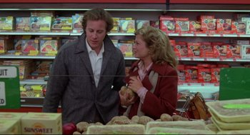 Movie still from “Chilly Scenes of Winter” (1979), directed by Joan Micklin Silver – A man and a woman standing in front of a display of food; Medium shot, Over the shoulder angle