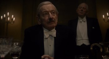 Movie still from “Darkest Hour” (2017), directed by Joe Wright – An older man wearing a tuxedo and a white bow tie; Close Up shot, Over the shoulder angle