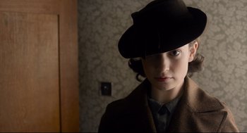 Movie still from “Darkest Hour” (2017), directed by Joe Wright – A young woman wearing a black hat and a brown coat; Close Up shot, High angle