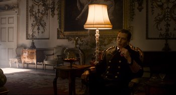 Movie still from “Darkest Hour” (2017), directed by Joe Wright – A man sitting in front of a lamp in a living room; Medium shot, Low angle