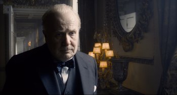 Movie still from “Darkest Hour” (2017), directed by Joe Wright – An older man in a suit and bow tie in front of a mirror; Close Up shot, Low angle