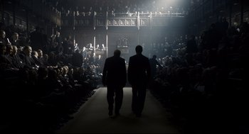 Movie still from “Darkest Hour” (2017), directed by Joe Wright – Two men are walking down a runway in front of an audience; Wide shot, High angle