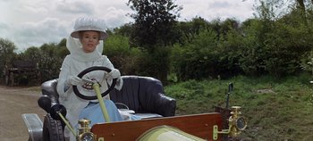 Movie still from “Chitty Chitty Bang Bang” (1968), directed by Ken Hughes – A woman sitting in a chair driving a vintage car; Medium shot, Low angle