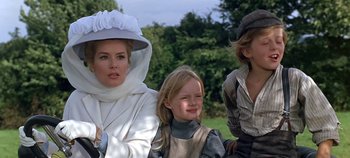 Movie still from “Chitty Chitty Bang Bang” (1968), directed by Ken Hughes – A woman and two children are sitting in a field; Medium shot, Low angle