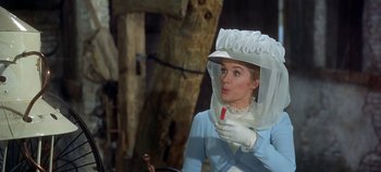 Movie still from “Chitty Chitty Bang Bang” (1968), directed by Ken Hughes – A woman in a white hat and gloves holding a red stick; Medium shot, Over the shoulder angle