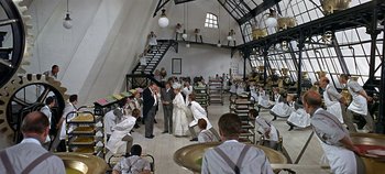 Movie still from “Chitty Chitty Bang Bang” (1968), directed by Ken Hughes – A group of people standing around in a room; Extreme Wide shot, High angle