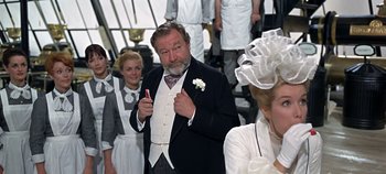 Movie still from “Chitty Chitty Bang Bang” (1968), directed by Ken Hughes – An older man giving a thumbs up in front of a group of people; Medium shot, Low angle