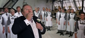 Movie still from “Chitty Chitty Bang Bang” (1968), directed by Ken Hughes – A man in a tuxedo blowing a kiss to a group of people; Medium shot, Low angle