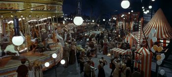 Movie still from “Chitty Chitty Bang Bang” (1968), directed by Ken Hughes – A crowd of people standing around a carousel at night; Extreme Wide shot, High angle