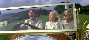 Movie still from “Chitty Chitty Bang Bang” (1968), directed by Ken Hughes – A man and two girls in the back of an old fashioned car; Medium shot, Low angle