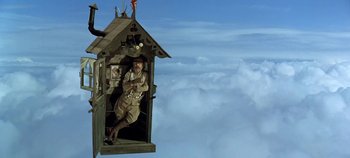 Movie still from “Chitty Chitty Bang Bang” (1968), directed by Ken Hughes – A man standing inside of a wooden house; Wide shot, Low angle