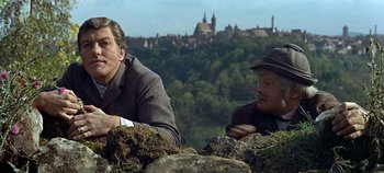 Movie still from “Chitty Chitty Bang Bang” (1968), directed by Ken Hughes – Two men sitting next to each other on top of a hill; Medium shot, Over the shoulder angle