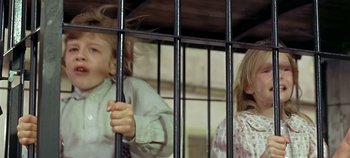 Movie still from “Chitty Chitty Bang Bang” (1968), directed by Ken Hughes – Two young children behind a metal fence; Close Up shot, Low angle