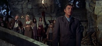 Movie still from “Chitty Chitty Bang Bang” (1968), directed by Ken Hughes – A man standing in front of a group of people in a cave; Medium shot, Low angle