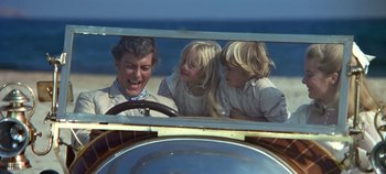 Movie still from “Chitty Chitty Bang Bang” (1968), directed by Ken Hughes – A man and two children in the back of an antique car; Medium shot, Low angle