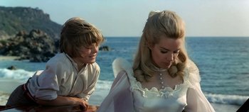 Movie still from “Chitty Chitty Bang Bang” (1968), directed by Ken Hughes – A young man and a young woman standing on a beach near the ocean; Medium shot, Over the shoulder angle