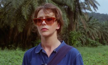 Movie still from “Chocolat” (1988), directed by Claire Denis – A woman wearing sunglasses and a blue shirt; Close Up shot, Low angle