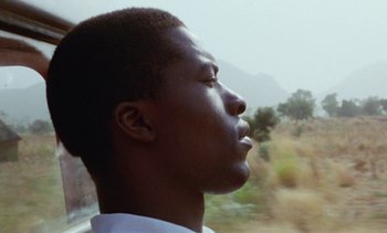 Movie still from “Chocolat” (1988), directed by Claire Denis – A young man is looking out a window; Close Up shot, Low angle