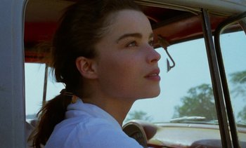 Movie still from “Chocolat” (1988), directed by Claire Denis – A beautiful young woman sitting in a car; Close Up shot, Over the shoulder angle