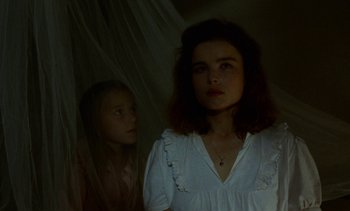 Movie still from “Chocolat” (1988), directed by Claire Denis – Two young girls standing next to each other in a dark room; Close Up shot, Low angle