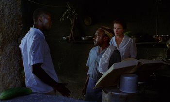 Movie still from “Chocolat” (1988), directed by Claire Denis – A group of people standing next to each other in a room; Medium shot, Over the shoulder angle