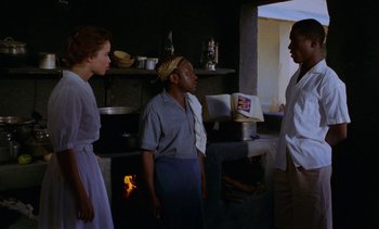 Movie still from “Chocolat” (1988), directed by Claire Denis – A group of people standing in front of an oven; Medium shot, Low angle